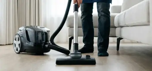Professional house cleaner vacuuming a living room floor with a canister vacuum cleaner, Pembroke Pines, FL.