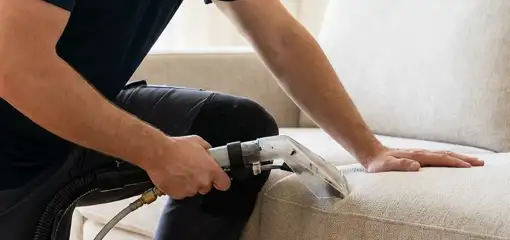 Professional upholstery cleaner deep-cleaning a fabric sofa with a handheld extraction tool, Pembroke Pines, FL.
